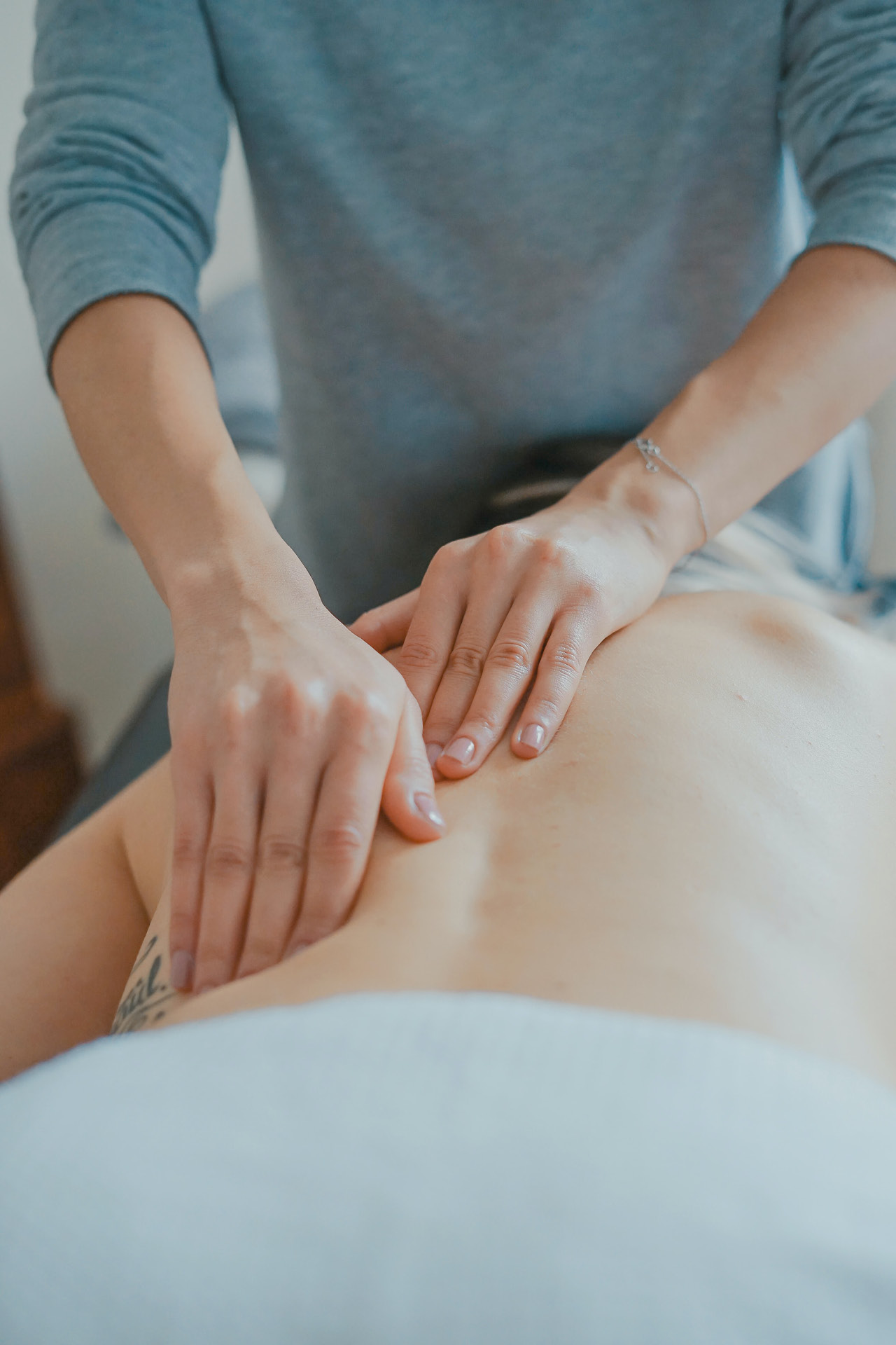 Osteopathin untersucht den Rücken einer Patientin mit den Händen.